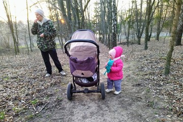 Mother and daughter with baby carriage in park