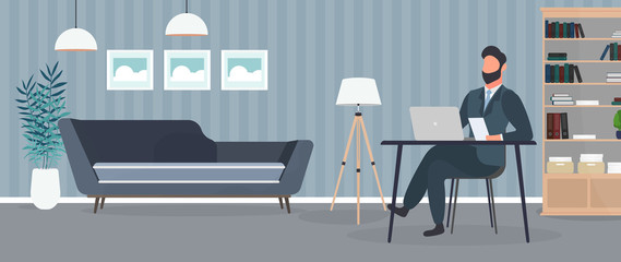 Naklejka na ściany i meble A guy with glasses sits at a table in his office. A man works on a laptop. Office, sofa, bookshelf, business man, floor lamp. Office work concept. Vector.