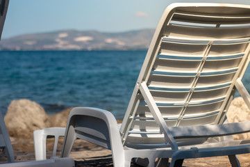 View of a plastic white foldable beach bed near the long beautiful blue sea