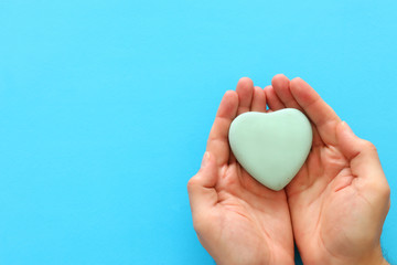 male hand holding heart over blue background. copy space, top view