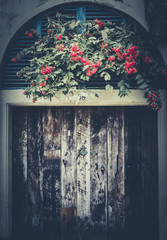 Old decay wooden door and flowers front view