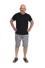 Bald man with sandals t-shirt and shorts, hand on hip