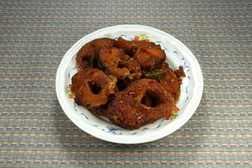 Fried crispy cutting striped Snakehead fish with herbal vegetable on the plate. Famous Thai hot and spicy menu in restaurant. 
