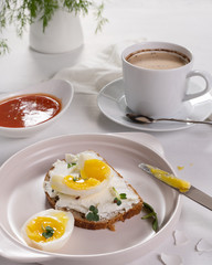 Breakfast with a cup of coffee. Open sandwich with cottage cheese and boiled eggs on a light plate. Above view