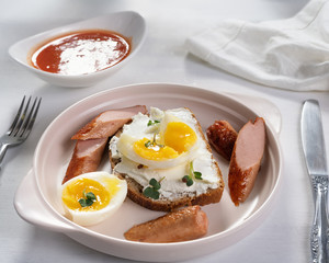 Open sandwich with sliced ​​sausages, cottage cheese and boiled eggs on a light plate. Above view