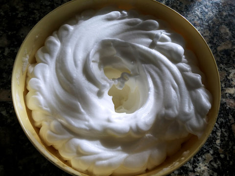 Luces y sombras sobre la suave crema de merengue blanco dentro de un cuenco.