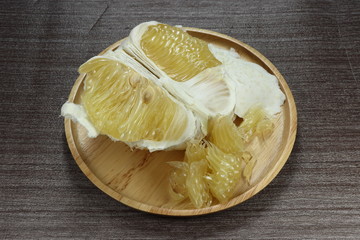 Peeled ripe grapefruit (Pomelo) on the wooden plate. Famous tropical fruit in Asia. Juicy and high vitamin snack. Mock up of product in fresh market. Sweet and sour dessert. 