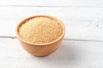 Brown cane sugar in bowl on vintage wooden background