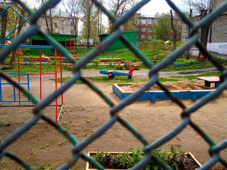 Fototapeta na wymiar Behind the grid is a colorful Playground in the kindergarten courtyard