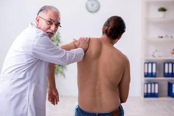 Young back injured man visiting experienced male doctor