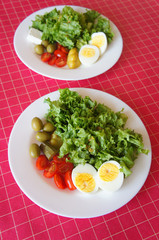 Spring salad with eggs, cherry tomatoes, olives, lettuce and french mustard dressing on colorful background . Healthy food concept.