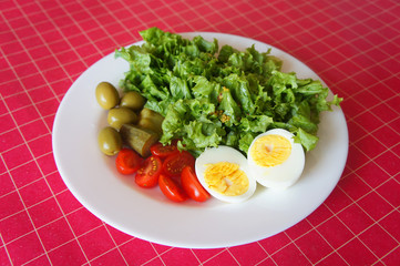 Spring salad with eggs, cherry tomatoes, olives, lettuce and french mustard dressing on colorful background . Healthy food concept.