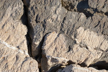 Textured surface of large rocks near the shore. Cracks between them