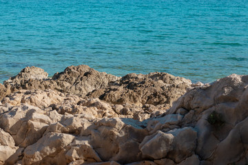 Stone rocks on the shore of split, bright blue warm sea water