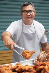 street hawker man working with his delicious traditional crispy fried chicken street food; concept...