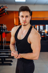 Muscular model young man in the gym. Fashion portrait of strong brutal guy. Male flexing his muscles. Sport workout bodybuilding concept.