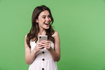 Image of excited attractive woman smiling and using cellphone