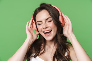 Image of cheerful nice woman singing while using wireless headphones