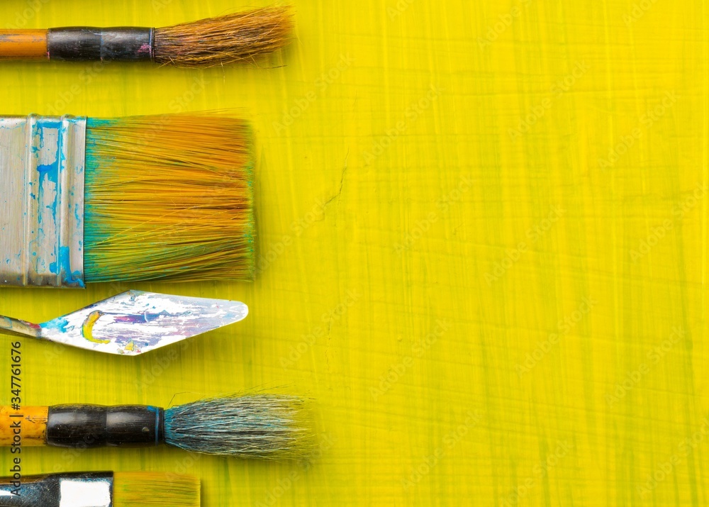 Poster artistic art supply utensils with brushes on yellow canvas background with copy space flat lay top v