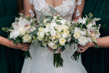 Bride and bridesmaid holding  bouquets of beautiful flowers 