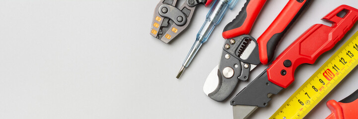 Tools of an electrician-installer or Builder on a gray table. Construction tools for repairs on a gray background. Top view with space for text. Banner