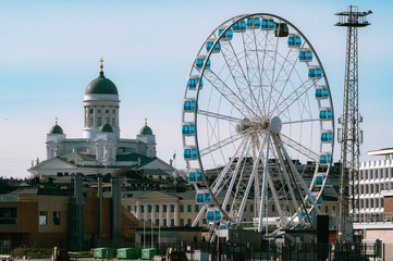 A summer cityscape from downtown with Helsinki Cathedral and city ferris wheel.