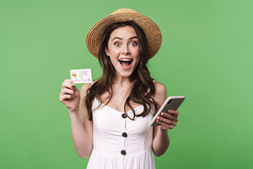 Image of excited woman holding credit card and using cellphone