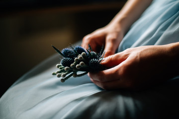 Close-up of the bride's hands holds a buttonhole