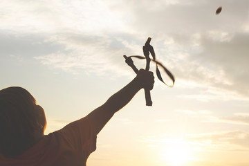 boy with his slingshot throws a stone at the target to hit