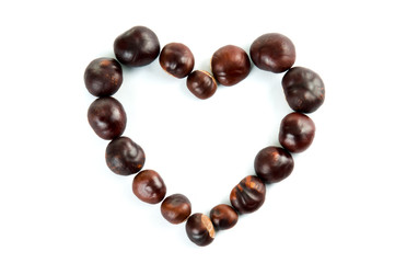 Heart made of fresh brown chestnuts isolated on white background as a design element for autumn love, Valentine's Day, Mother's Day and other related themes. Top view. Studio shot