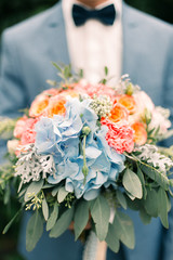 Stylish groom holding wedding bouquet