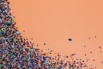 Recycled plastic pellets collected from the sea water, flatlay on a soft orange  background. Colorful pieces. Rethinking the environment by reducing or reusing plastics. Circular economy concept