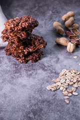 Oatmeal cookies pile with peanuts and oat flakes on concrete background. Healthy snack. Vertical picture.