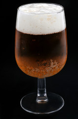 Verre de bière blonde close-up sur fond noir