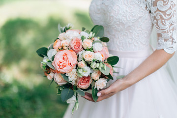 Bride in white dress holding beautiful bouquet. Green background
