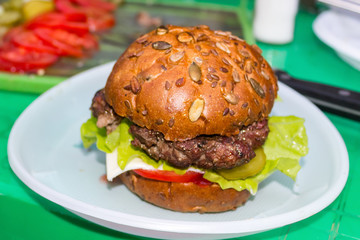 appetizing fresh homemade burger with with meat, cheese and lettuce on a green table. Delicious fast food concept.  hamburger day cancelled