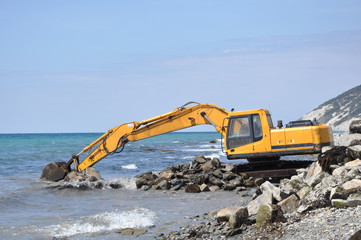 excavator cleans the sea beach