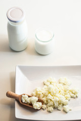 Milk kefir grains in wooden spoon with a glass of kefir in the back