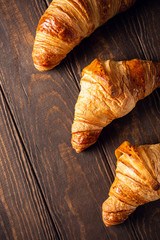 Food background with freshly baked sweet croissants on old wooden table. Breakfast or brunch concept with copy space, top view
