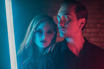 Fashion portrait of couple: beautiful woman and handsome man posing in colorful bright neon uv blue...