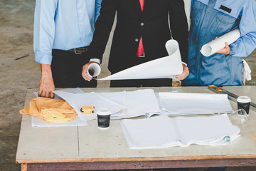 Engineer team and worker looking paper plans at construction site.