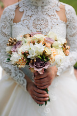 Bride in white dress holding a bouquet of white flowers and greenery