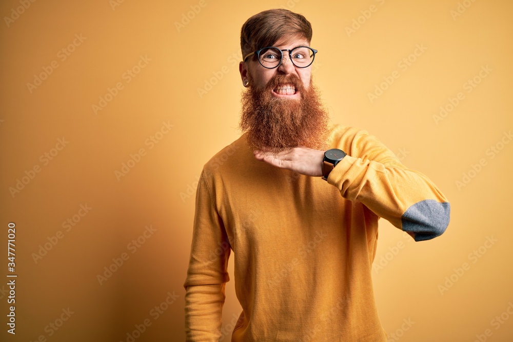 Canvas Prints handsome irish redhead man with beard wearing glasses over yellow isolated background cutting throat