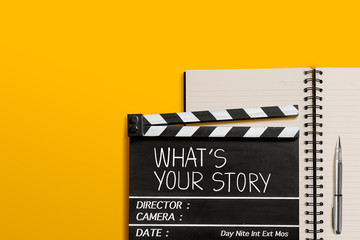 Fototapeta na wymiar What's your story.Text title on movie clapperboard and notebook on yellow background