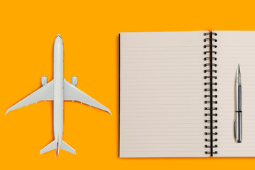Aircraft model and diary book on yellow color background