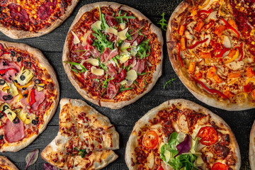 Fototapeta na wymiar Tasty hot italian pizzas set on black wooden table. Pizzeria menu. Concept poster for Restaurants or pizzerias
