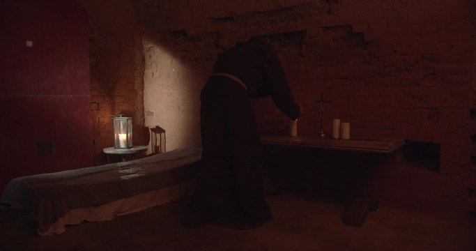 Monk lighting candles in front of the altar in the dark room.