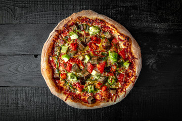 Tasty hot italian pizza vegetarian with eggplant, zucchini, tomatoes on black wooden table. Pizzeria menu. Concept poster for Restaurants or pizzerias