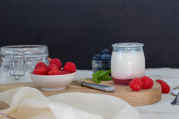 Healthy morning breakfast with fresh yogurt in clear glass and berries on a wooden board. Healthy life concept.