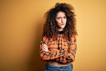 Young beautiful brunette woman with curly hair and piercing wearing casual t-shirt skeptic and nervous, disapproving expression on face with crossed arms. Negative person.